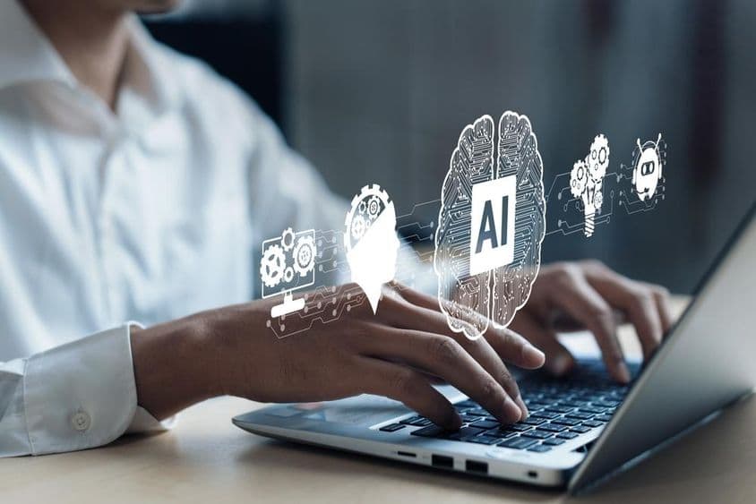 投影的笔记本显示 AI 大脑和其他元素。人手在电脑上操作。