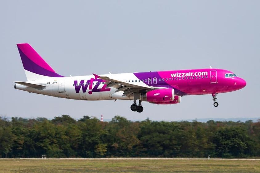 Wizz Air飞机在低空飞行,背景是森林。