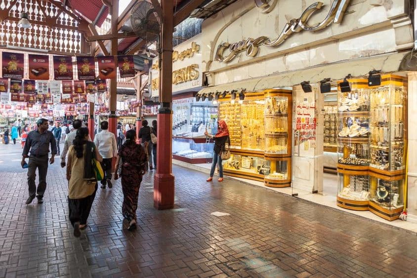 迪拜黄金市场,一家展示黄金珠宝的商店,行人经过。