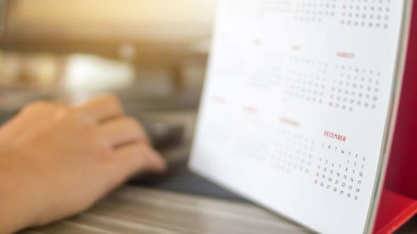 一个手放在日历旁,月份模糊,十二月清晰可见。