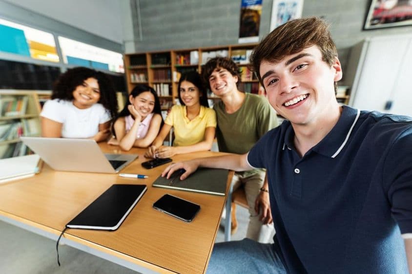 学生在图书馆学习,桌上放有笔记本、手机和纸质记事本。