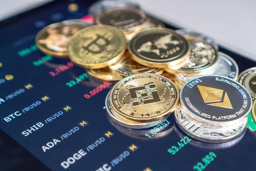 放在显示加密交易率的手机屏幕上的以太坊和比特币硬币。