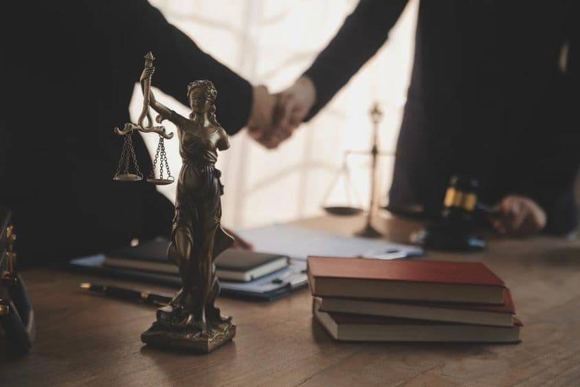 一位律师与客户谈判,桌上可见正义女神像。