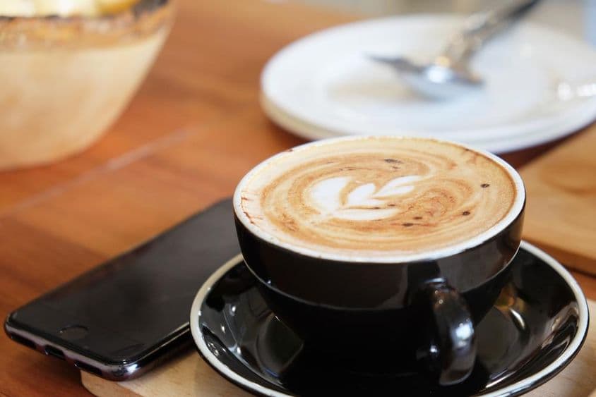 桌上的一杯卡布奇诺和旁边的一部电话。