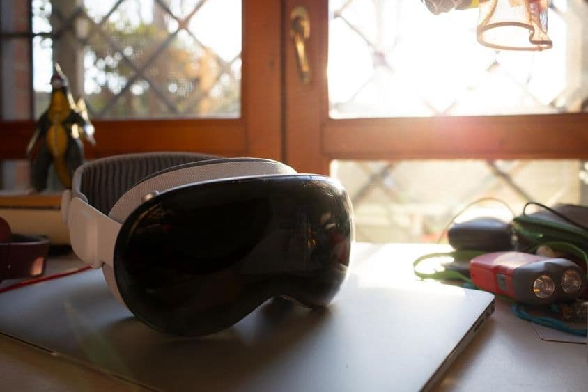 苹果Vision Pro放在桌子上的笔记本上。