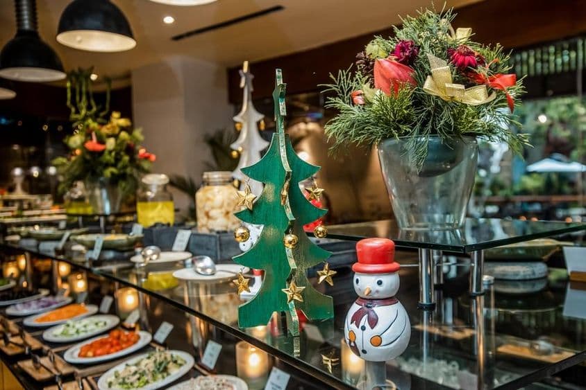 餐厅内蔬菜柜台上的小雪人,旁边有木质圣诞树。