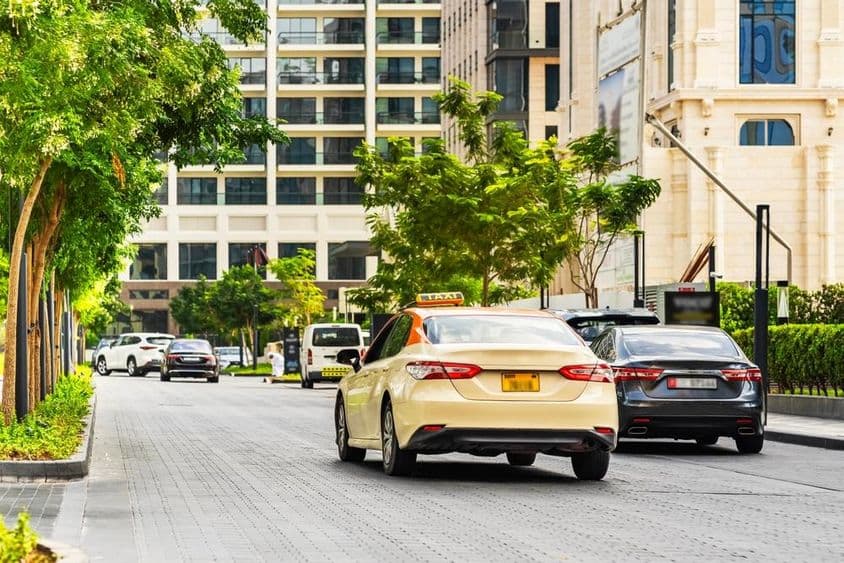 迪拜道路上的汽车,前景是一辆出租车,背景是房屋。