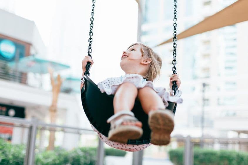 幼儿园院子里快乐荡秋千的小女孩。