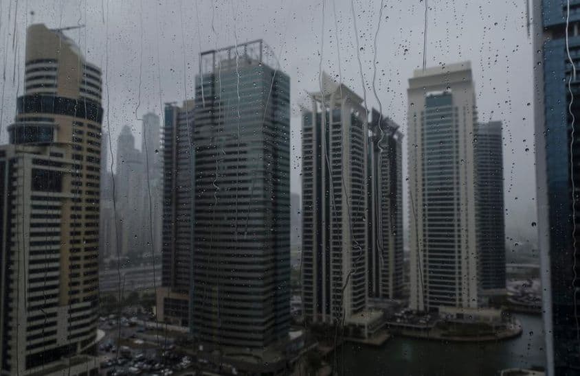 现代迪拜商业天际线的雨湿窗户特写。