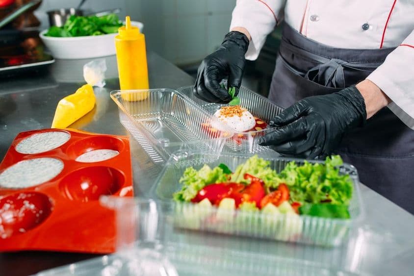 厨师在餐馆准备食物并将其打包在一次性容器中。