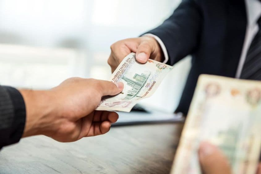 商人向合作伙伴递交阿联酋迪拉姆货币