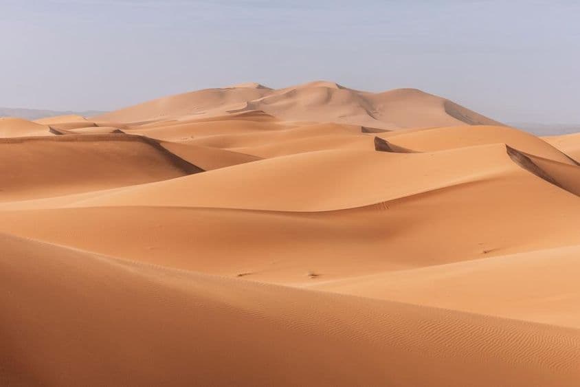 高耸的沙丘,金色的夕阳笼罩着平静宁静的景观。