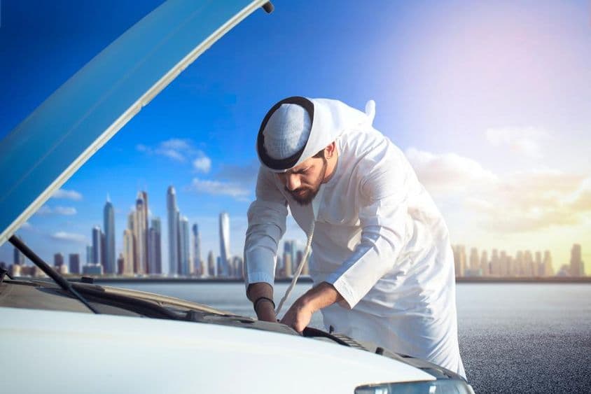 一位阿拉伯男子正在检查他的汽车,车盖已打开。