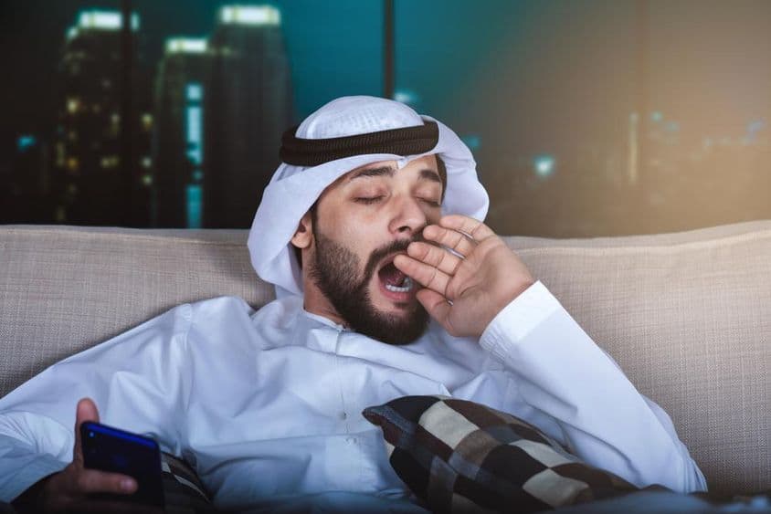 阿拉伯男子边看电视边打哈欠