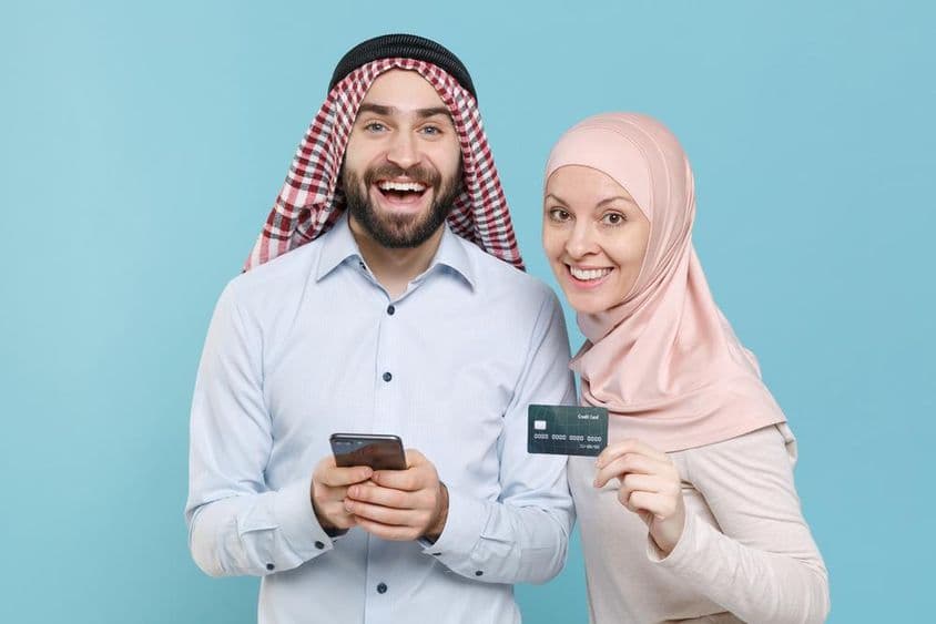 微笑的情侣拿着信用卡和手机。