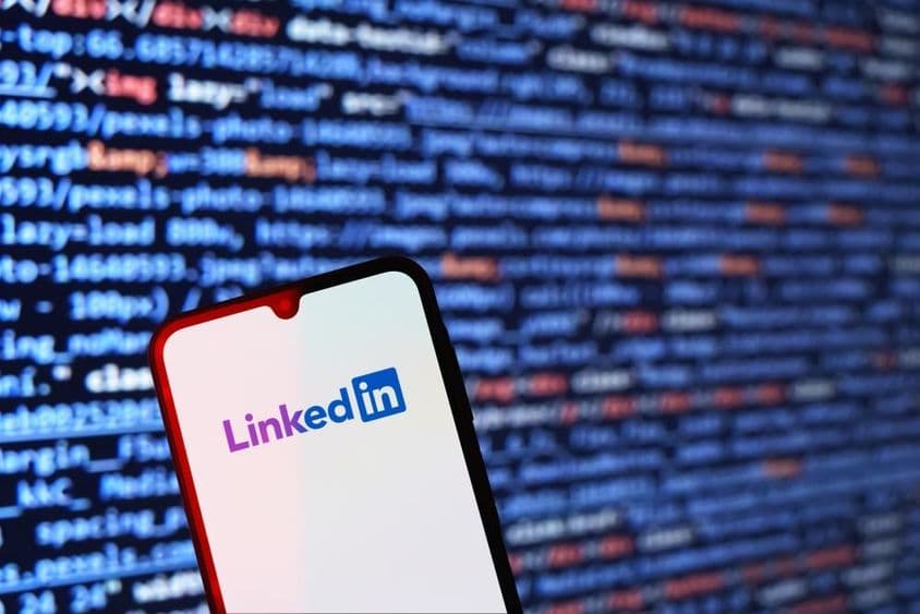 带代码片段背景的智能手机展示LinkedIn徽标
