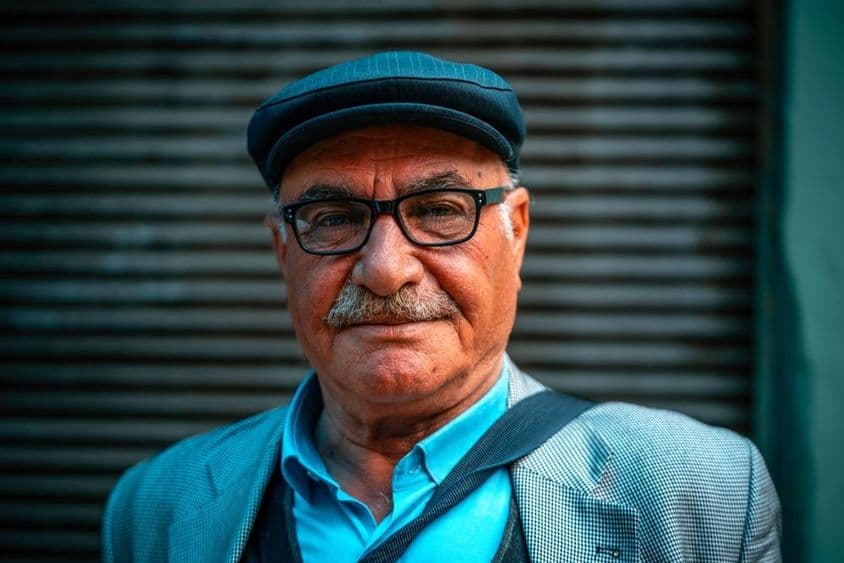 戴帽子的老年男性站在街上。