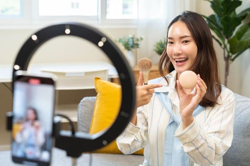 年轻的网红女性博主使用智能手机进行视频直播。