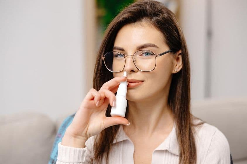 使用鼻喷剂缓解呼吸的年轻女性。