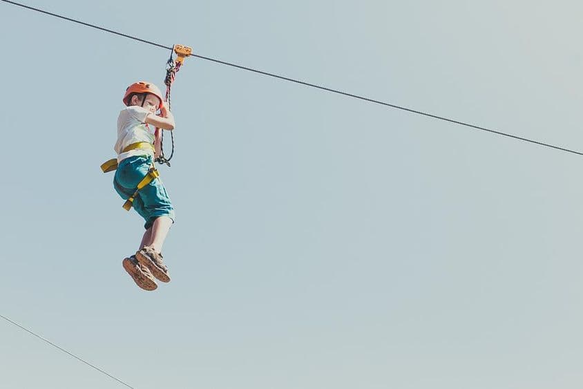 男孩在阳光明媚的夏日里攀登冒险公园
