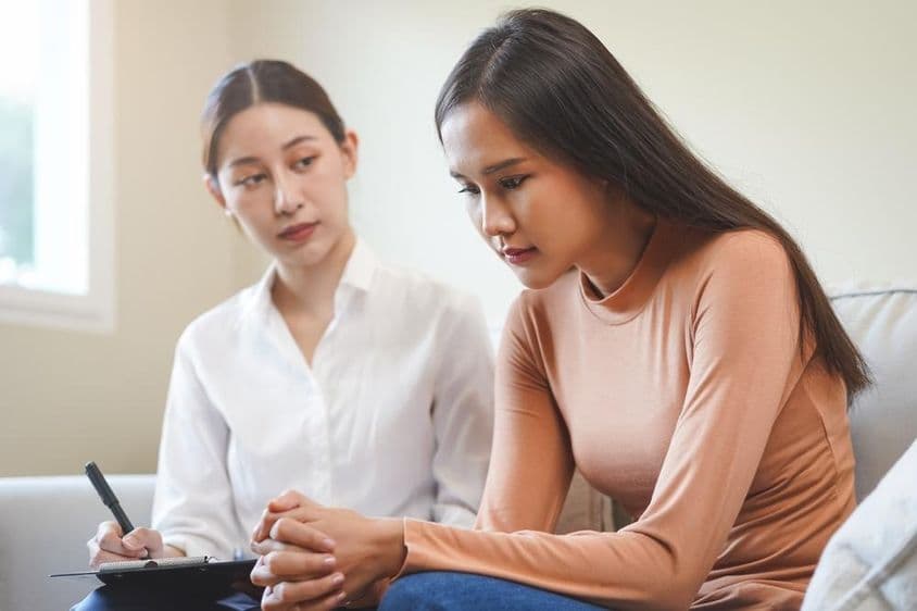 悲伤的亚洲年轻女性与心理学家进行咨询。