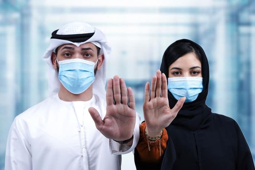 戴医疗口罩的阿拉伯男女做出停止手势