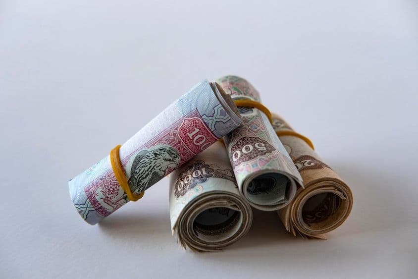 一叠卷起并堆放的阿联酋迪拉姆货币和硬币。