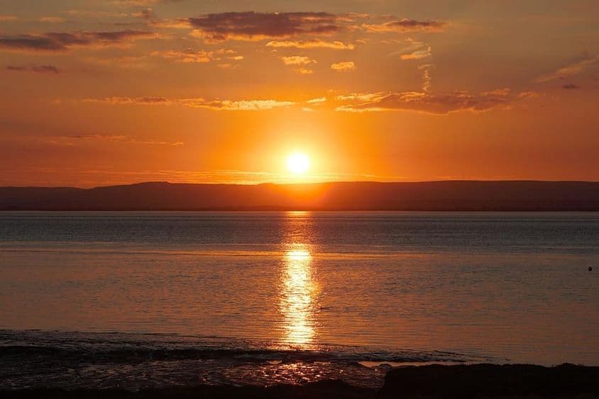 夏至期间,日落反射在水面和云层上。