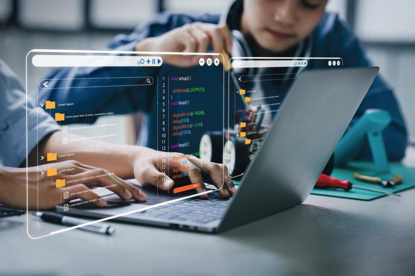 青少年学生正在进行涉及机器人臂和机器人汽车的作业。