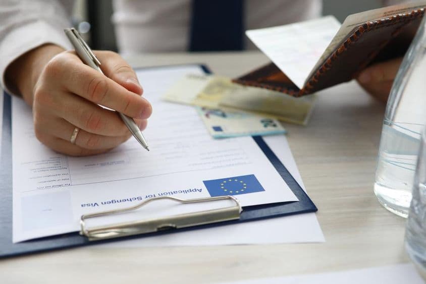 一名男子手持护照,正在填写申根签证申请信息。