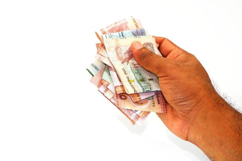 手中握有迪拉姆钞票。