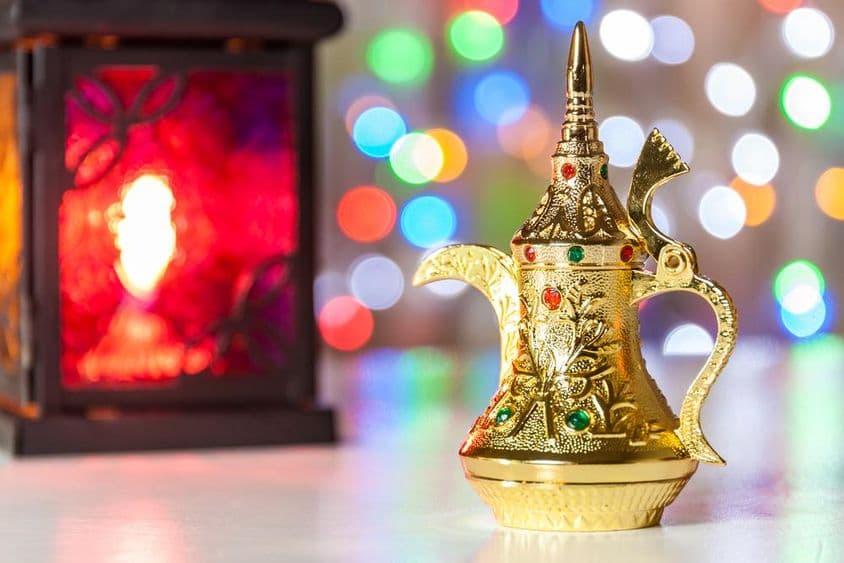 阿拉伯咖啡壶和灯,背景是五光十色的模糊灯光。