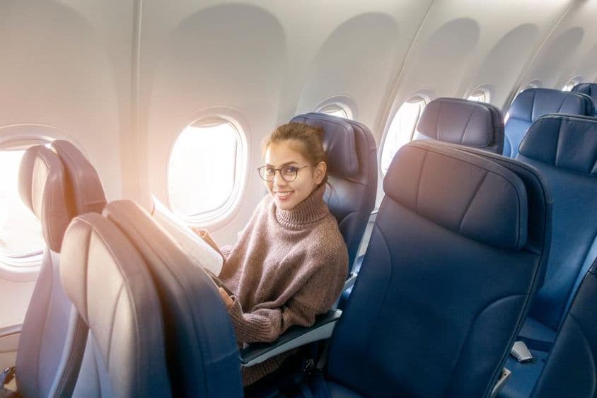 亚洲女性在飞机上阅读杂志。