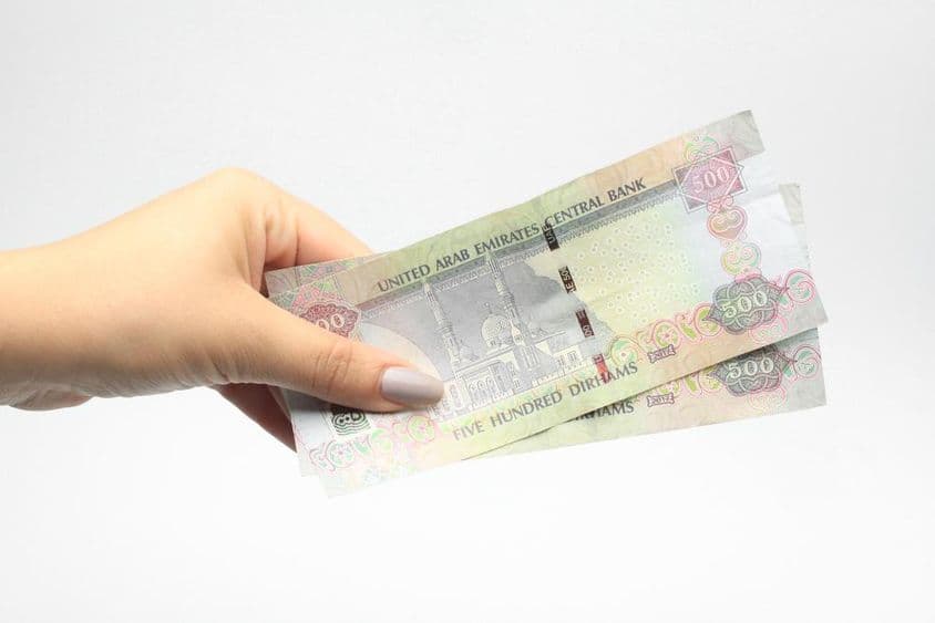 一位女士手持500迪拉姆货币。