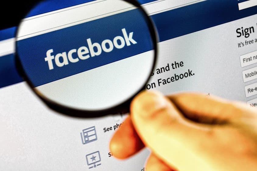 放大镜下显示的监视器上的Facebook首页截图。