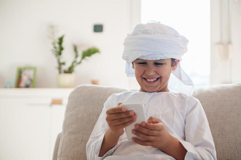 阿拉伯男孩在家使用智能手机。