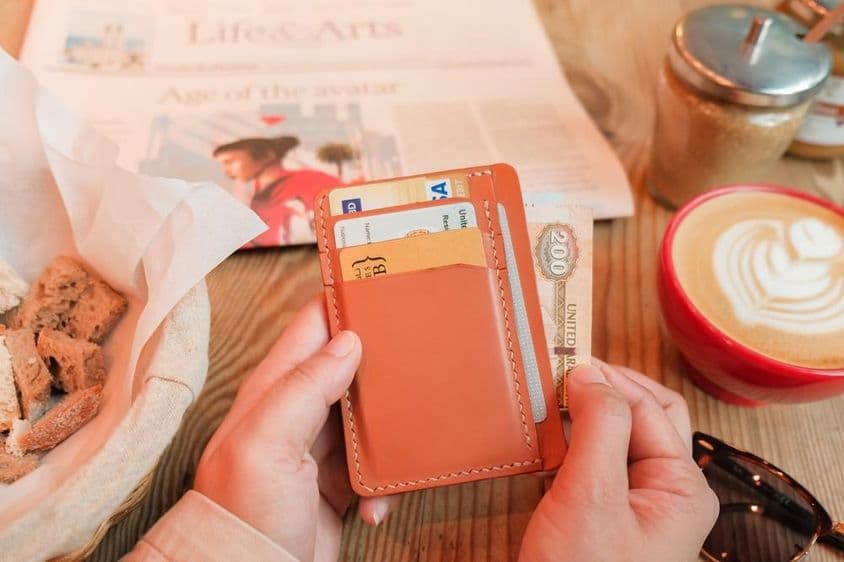 一只手从棕色皮革卡包中取出200阿联酋迪拉姆。