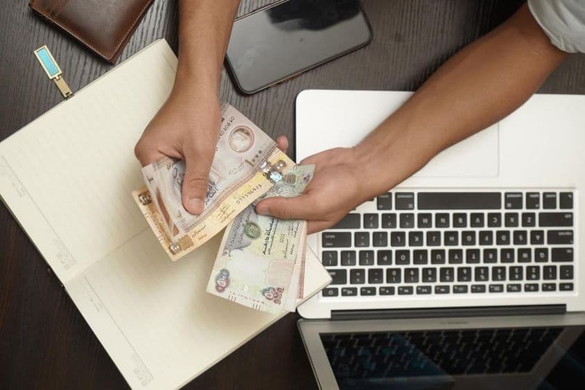 一名男子正在数一叠阿联酋迪拉姆纸币。