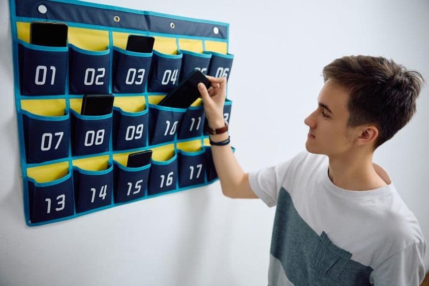 学生将智能手机放入墙上的手机收纳架。