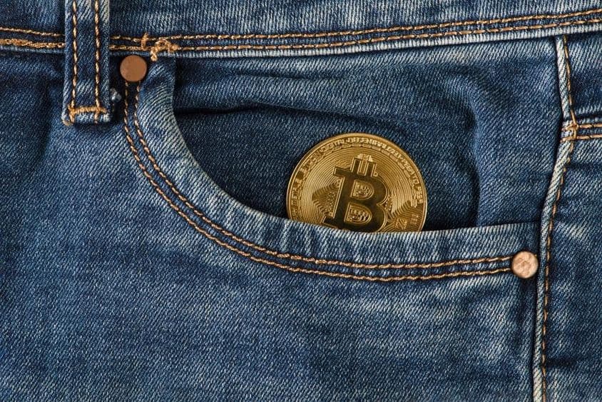 一枚金色的比特币放在牛仔裤口袋中。
