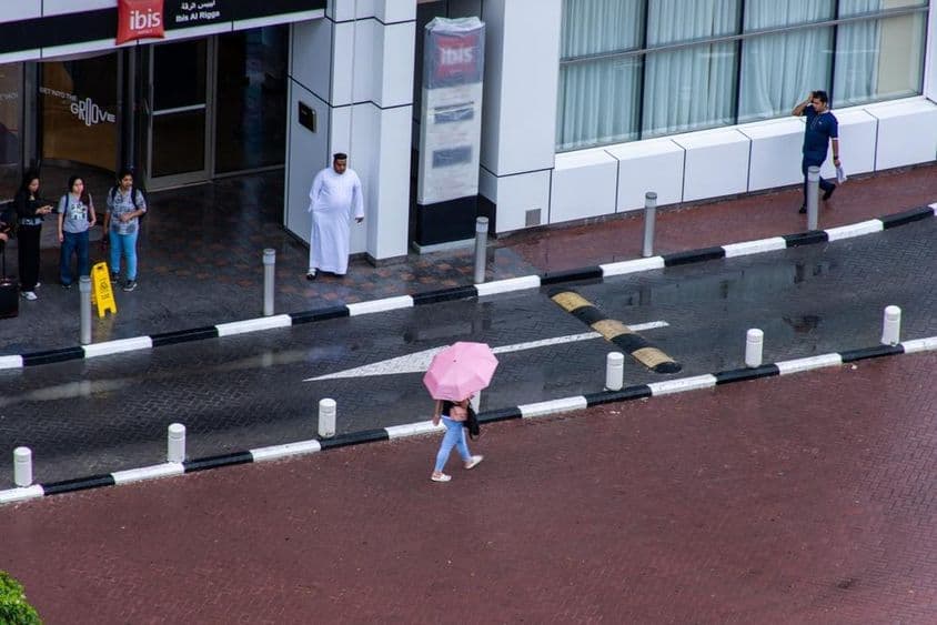 迪拜市区雨中打伞行走的女孩。
