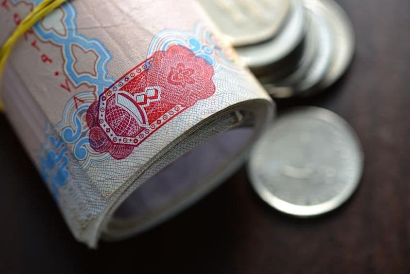 卷起的阿联酋迪拉姆以及几枚硬币。