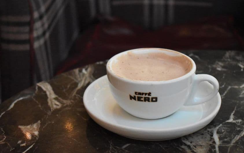 在Caffe Nero的大理石桌上放置的一杯热巧克力。