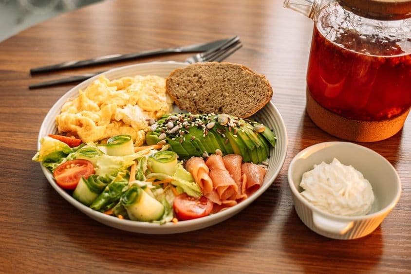 健康早餐,包含鸡蛋、牛油果、绿叶蔬菜、沙拉和覆盆子茶。