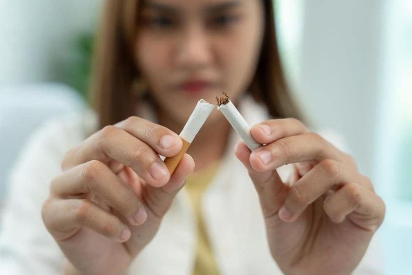 禁止吸烟,一名女子把一支烟折成两半。