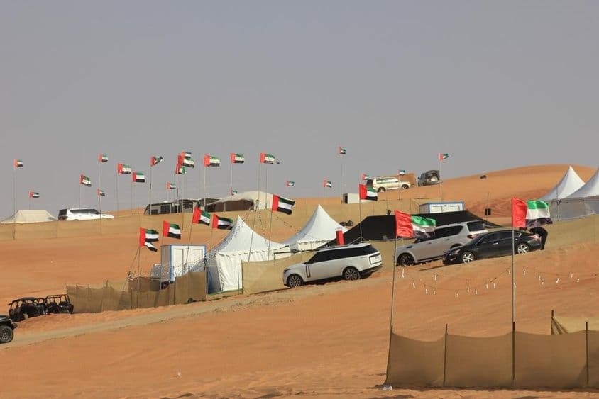 越野车辆与野营帐篷在广阔的沙丘上。