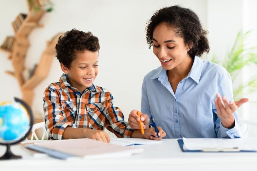 年轻女教师向小男孩讲解课程。