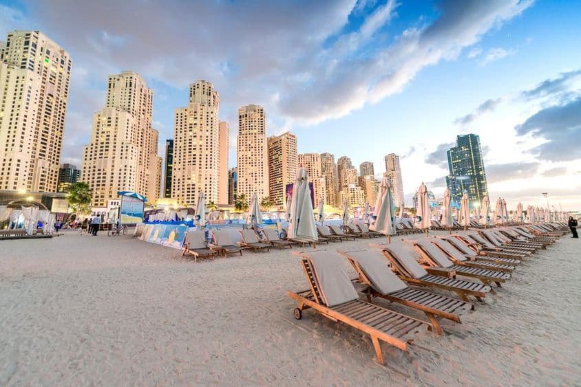 迪拜Marina Beach的日落,带有沙滩椅和摩天大楼。