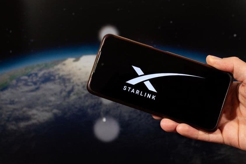一只男性的手右手握着印有 Starlink 标志的智能手机。